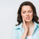 Une femme se touche le côté du visage à cause d'une douleur dentaire